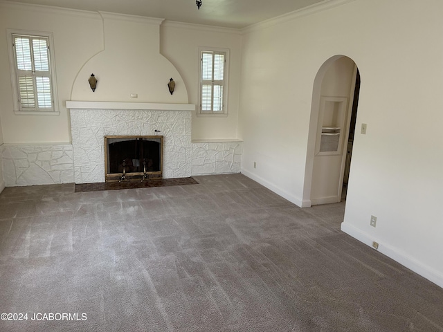 unfurnished living room with ornamental molding, a stone fireplace, and carpet flooring