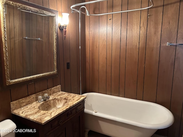 bathroom with toilet, vanity, wooden walls, and a washtub