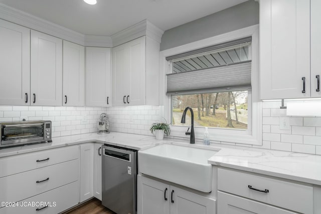 kitchen with dishwasher, light stone counters, white cabinetry, and sink