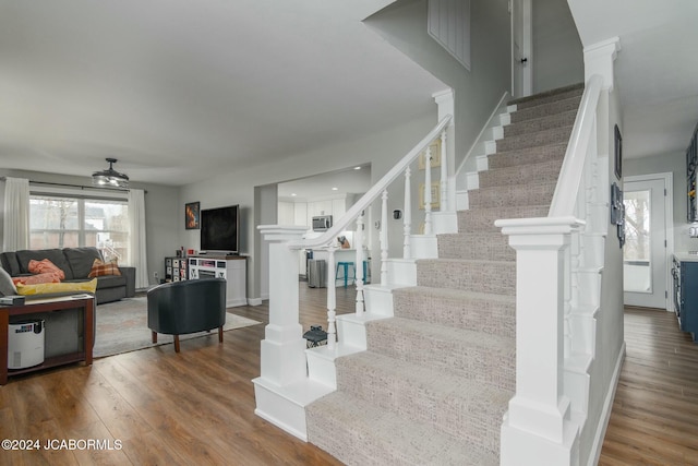 stairs featuring ceiling fan and hardwood / wood-style floors