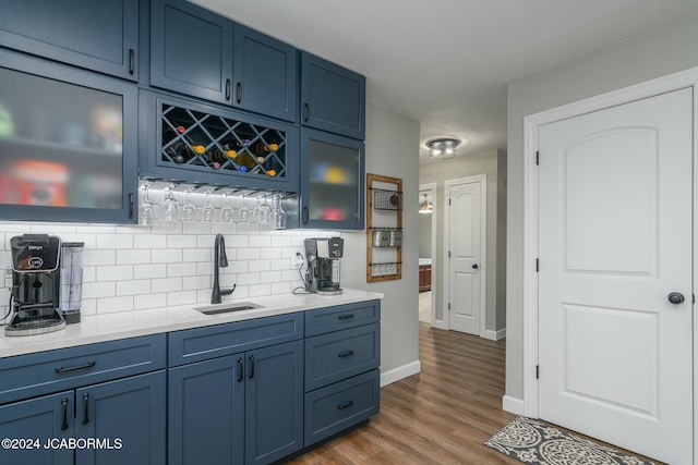 bar featuring decorative backsplash, blue cabinetry, and sink