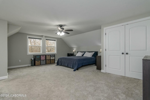 bedroom featuring ceiling fan, a closet, light carpet, and vaulted ceiling