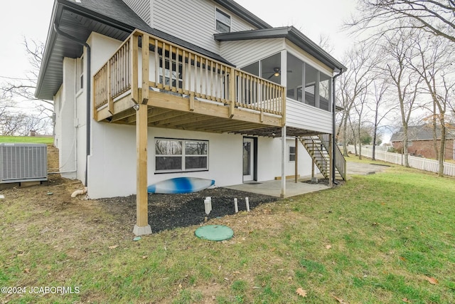 rear view of property with a lawn, a sunroom, central air condition unit, a wooden deck, and a patio