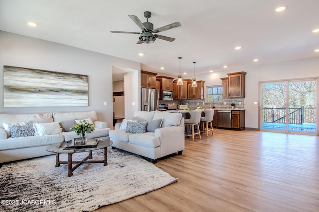 living room with sink, light hardwood / wood-style flooring, and ceiling fan