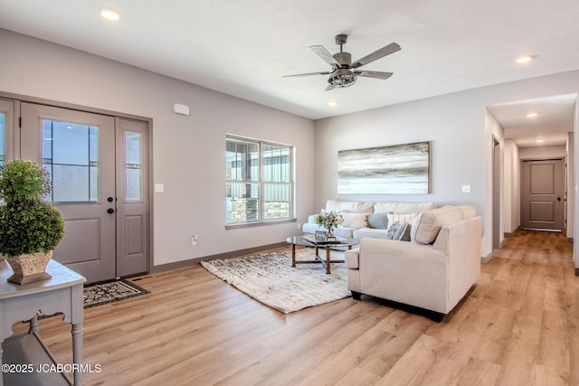 living room with ceiling fan and light hardwood / wood-style flooring