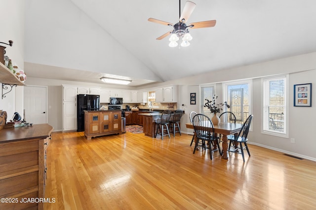 1548 Skyview, Holts Summit, MO 65043 - dining room with high vaulted ceiling, a ceiling fan, light wood-type flooring, and baseboards