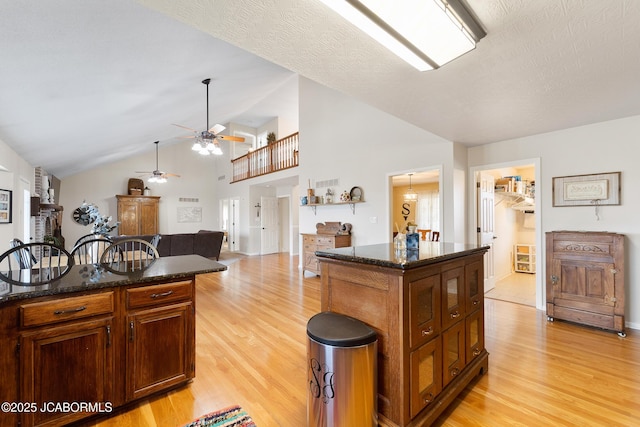 1548 Skyview, Holts Summit, MO 65043 - kitchen featuring light wood finished floors, ceiling fan, dark stone counters, a center island, and high vaulted ceiling