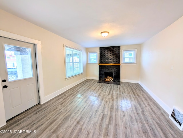 unfurnished living room featuring a brick fireplace and light hardwood / wood-style flooring