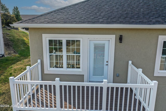 doorway to property with stucco siding and roof with shingles