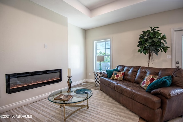 living room featuring a glass covered fireplace, light wood-style flooring, and baseboards