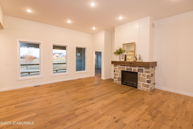 living room featuring recessed lighting, light wood-style flooring, baseboards, and a stone fireplace