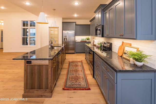kitchen featuring tasteful backsplash, recessed lighting, light wood-style flooring, stainless steel appliances, and a sink