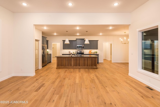 kitchen with tasteful backsplash, an inviting chandelier, light wood-style floors, visible vents, and stainless steel appliances