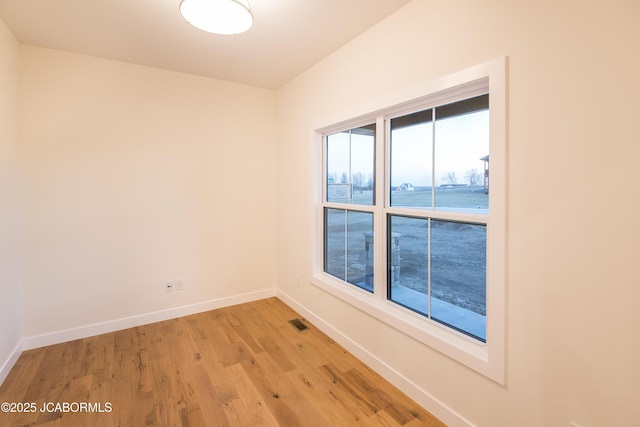 spare room with visible vents, baseboards, and light wood finished floors