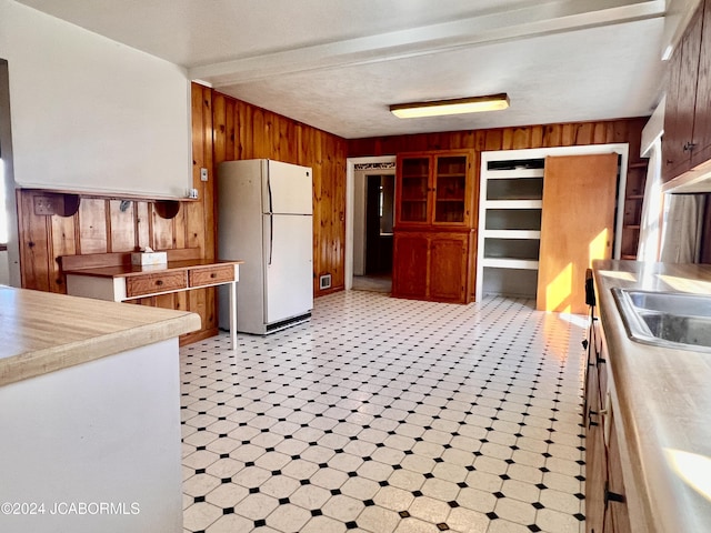 kitchen featuring sink, white fridge, and wood walls