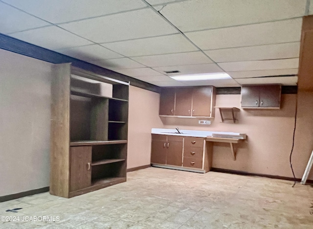 kitchen with a paneled ceiling, dark brown cabinetry, and sink