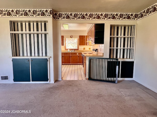 kitchen featuring stove, light colored carpet, and sink