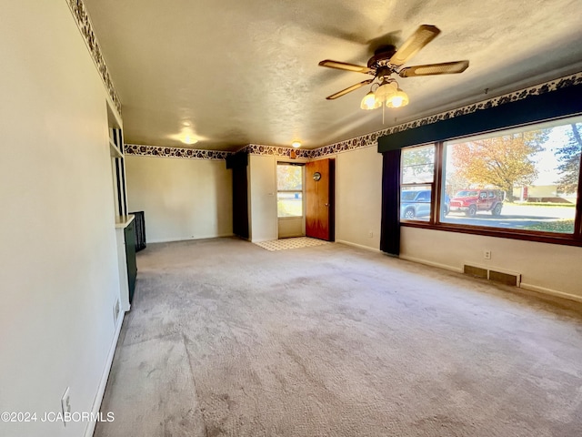 carpeted spare room featuring ceiling fan and a textured ceiling