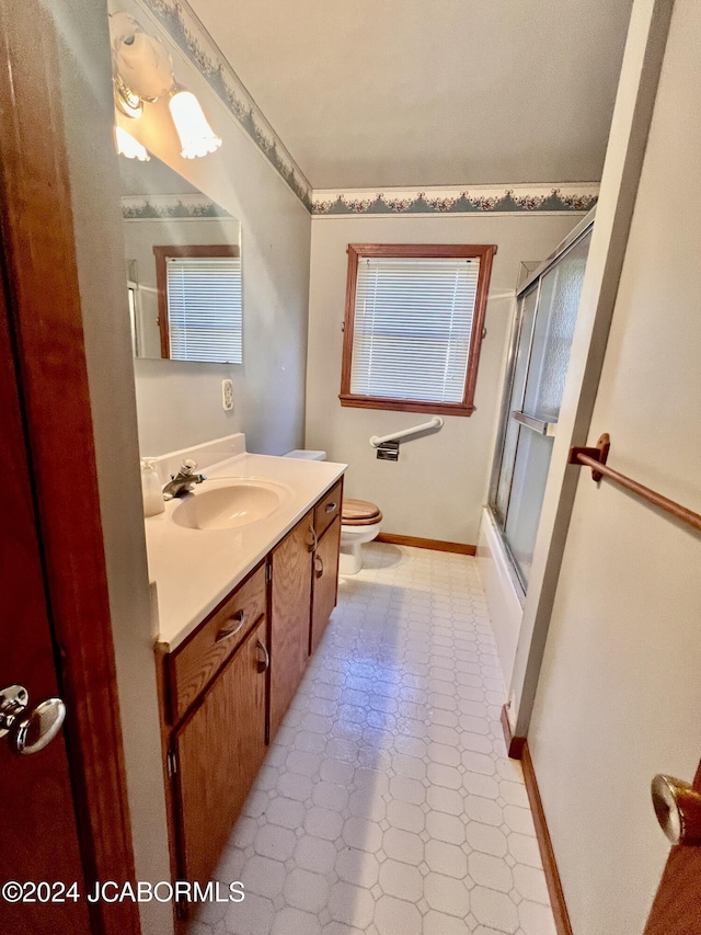 full bathroom featuring tile patterned flooring, vanity, toilet, and bath / shower combo with glass door