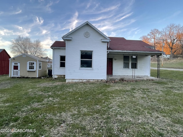 back of house with a lawn, a porch, and a shed