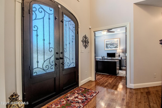 foyer featuring wood finished floors, french doors, baseboards, and arched walkways