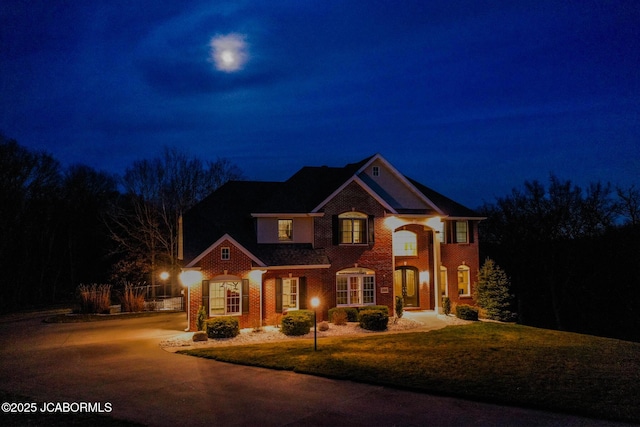 view of front of property with brick siding and a yard