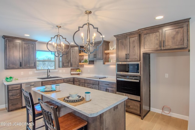 kitchen with appliances with stainless steel finishes, a notable chandelier, sink, hanging light fixtures, and a center island