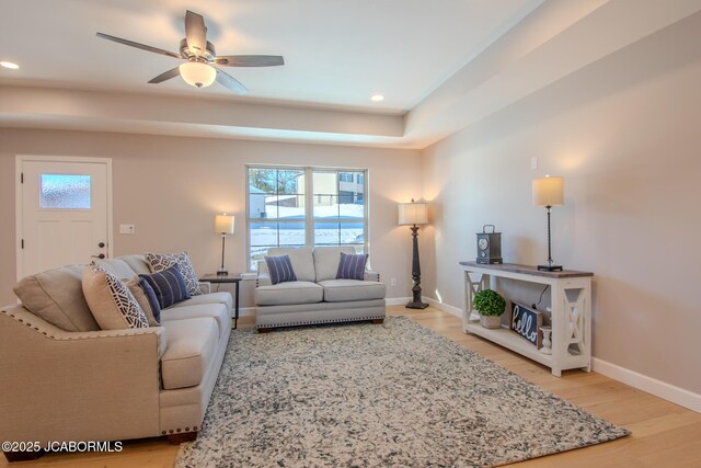 living room featuring ceiling fan, a raised ceiling, and hardwood / wood-style flooring