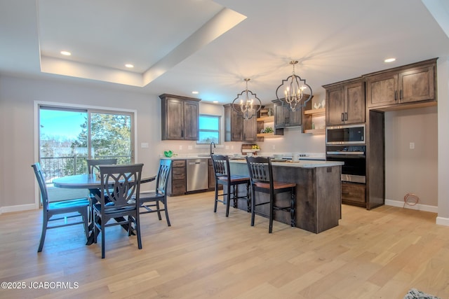 kitchen featuring pendant lighting, appliances with stainless steel finishes, a kitchen island, an inviting chandelier, and light hardwood / wood-style floors