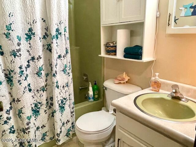 full bathroom with toilet, shower / bath combo with shower curtain, and vanity