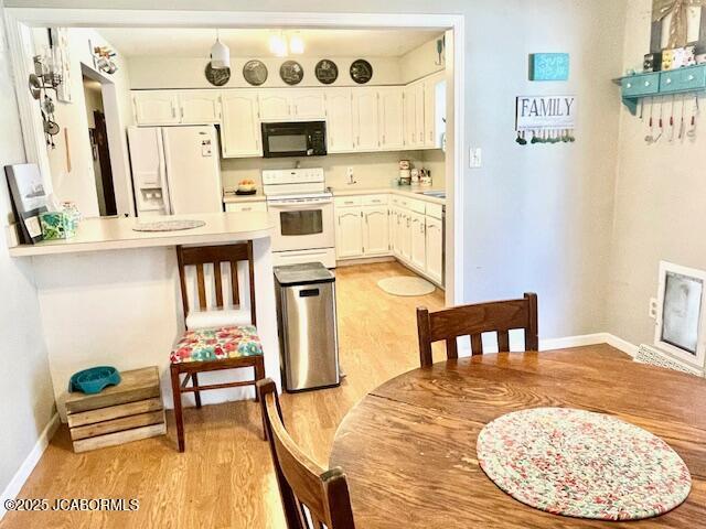 kitchen with white appliances, white cabinetry, kitchen peninsula, and light hardwood / wood-style floors