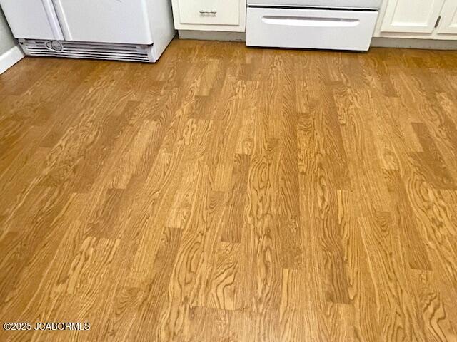 room details featuring white cabinetry, fridge, range, and light wood-type flooring