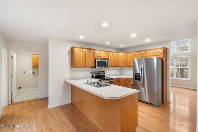 31500 Skyline Dr, California, MO 65018 - kitchen featuring appliances with stainless steel finishes, a peninsula, backsplash, light countertops, and light wood-style flooring