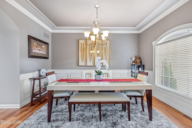 dining space with ornamental molding, a chandelier, and wood-type flooring