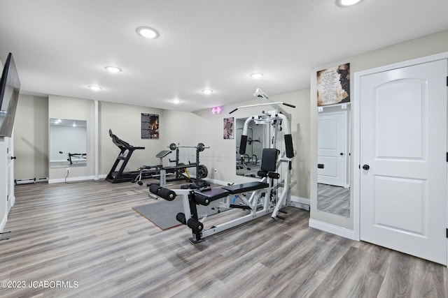 exercise room featuring light hardwood / wood-style flooring and a textured ceiling