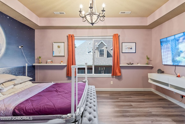 bedroom with hardwood / wood-style flooring, a raised ceiling, and a notable chandelier