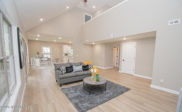 living room with high vaulted ceiling and light hardwood / wood-style flooring