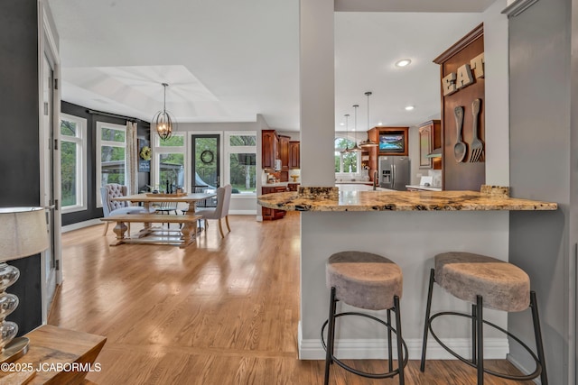 1503 State Highway Z, Centertown, MO 65023 - kitchen featuring light stone counters, a kitchen bar, stainless steel fridge, light wood finished floors, and brown cabinets