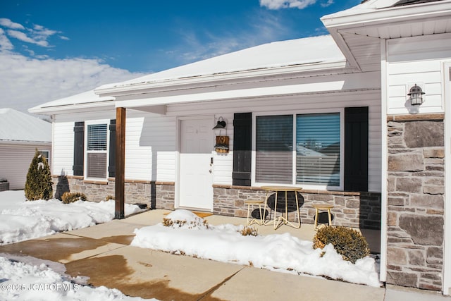 snow covered property entrance featuring a porch