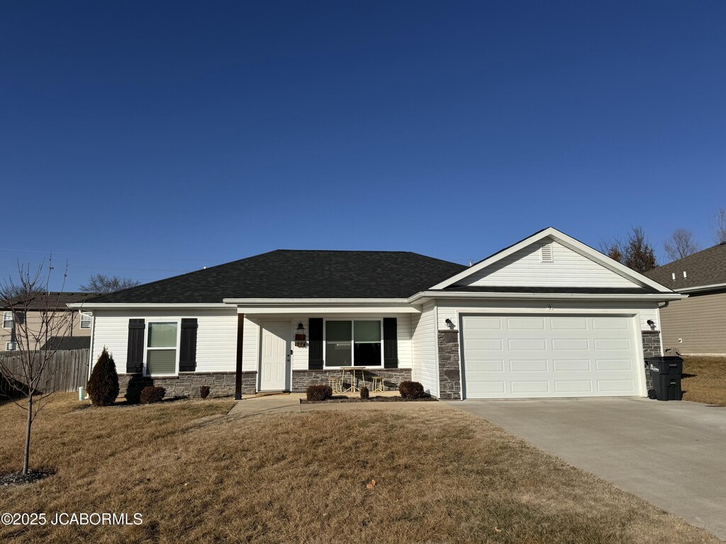 ranch-style home with a garage, a front lawn, and covered porch