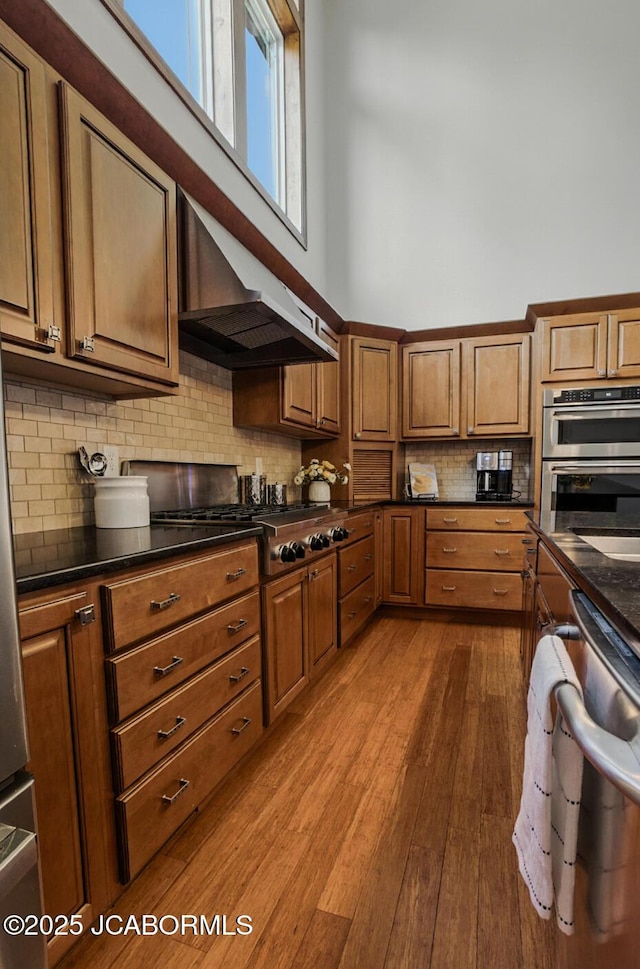 5004 Bates Creek Ct, Columbia, MO 65201 - kitchen with under cabinet range hood, dark countertops, decorative backsplash, stainless steel appliances, and dark wood finished floors
