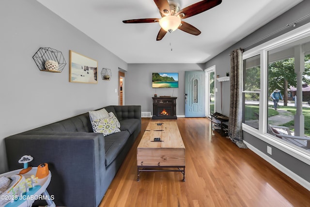 2213 Tanner Bridge Rd, Jefferson City, MO 65101 - living room with a lit fireplace, wood finished floors, and ceiling fan
