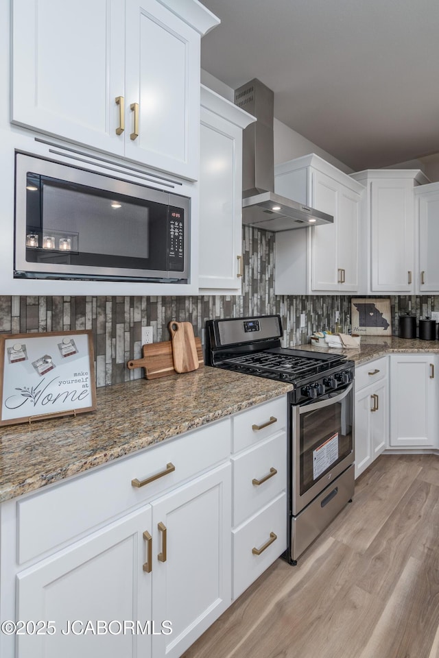 kitchen with white cabinetry, wall chimney exhaust hood, tasteful backsplash, and stainless steel appliances