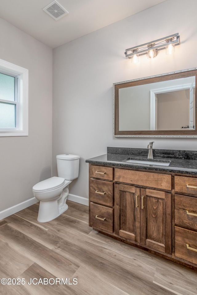 bathroom with visible vents, baseboards, toilet, wood finished floors, and vanity