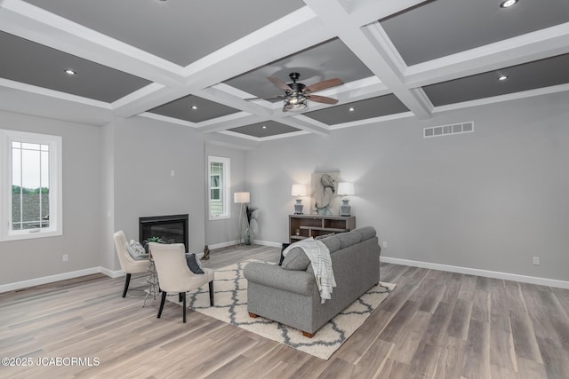 living room featuring baseboards, a glass covered fireplace, and coffered ceiling