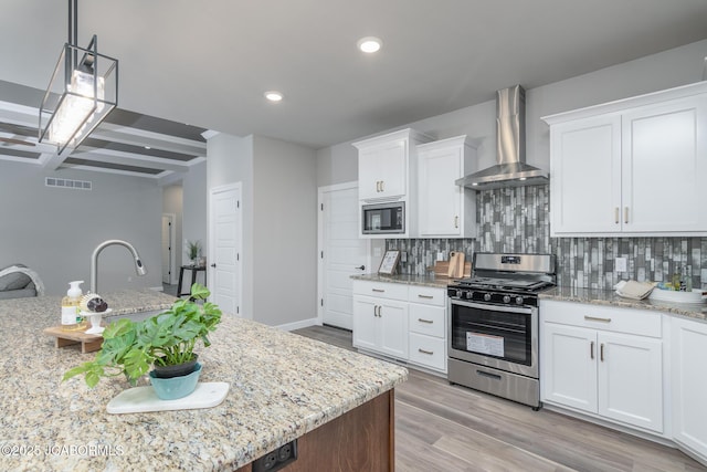 kitchen featuring tasteful backsplash, stainless steel gas range, built in microwave, visible vents, and wall chimney range hood