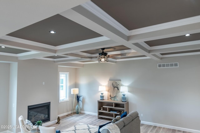 living room with visible vents, light wood finished floors, baseboards, beam ceiling, and coffered ceiling