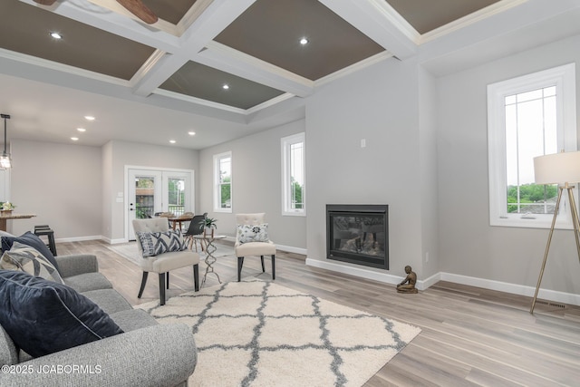 living area with coffered ceiling, beamed ceiling, a glass covered fireplace, and a healthy amount of sunlight