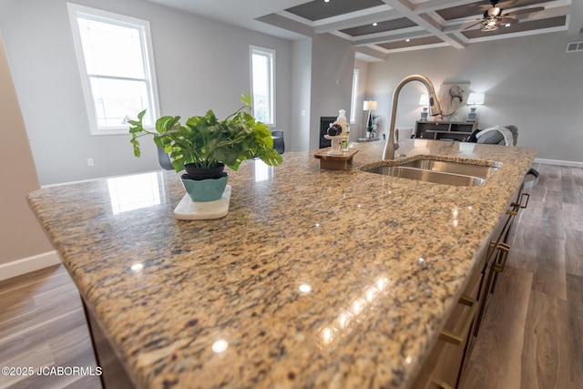 kitchen with baseboards, wood finished floors, beam ceiling, a sink, and coffered ceiling