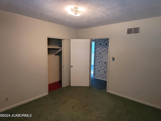 unfurnished bedroom with dark carpet and a closet